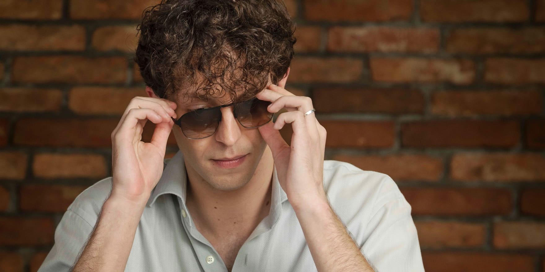 Junger Mann nimmt seine Sonnenbrille zur Pflege ab. Tipps von Optiker GRONDE