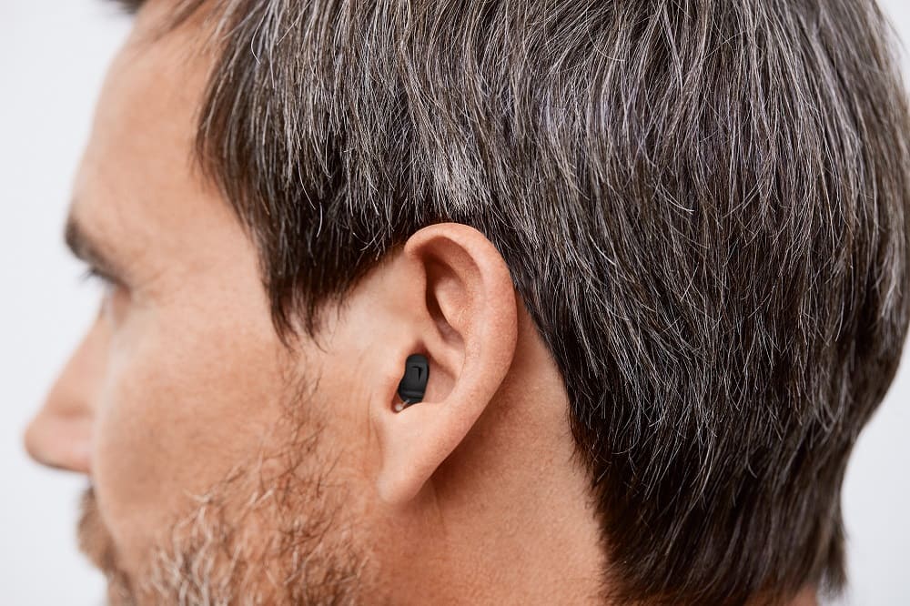 Mann trägt Im-Ohr-Hörgerät Signia NX Insio IIC von Hörakustik Gronde, fast unsichtbar